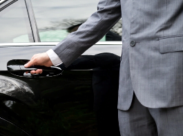 Chauffeur VTC qui ouvre la portière d'un véhicule noir haut de gamme